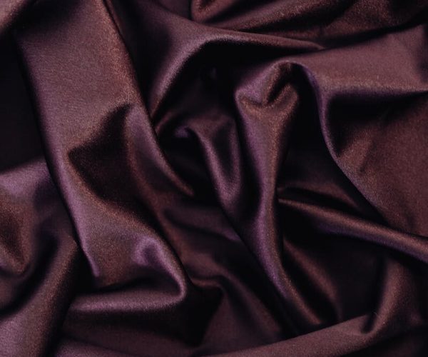 Close-up of crinkled, shining purple satin fabric, highlighting its smooth texture and elegant drapery.